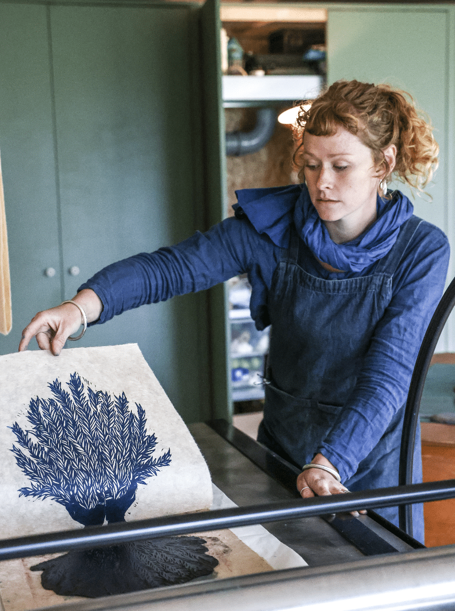 Photograph of Rosanna in her studio peeling a print on paper fresh from the press