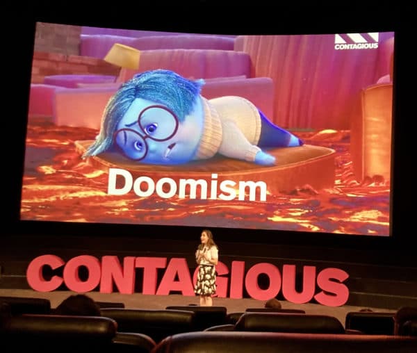 Image of 'Doomism' shown with cartoon character looking seldom. Shown on the big screen from photographers view in cinema seat.